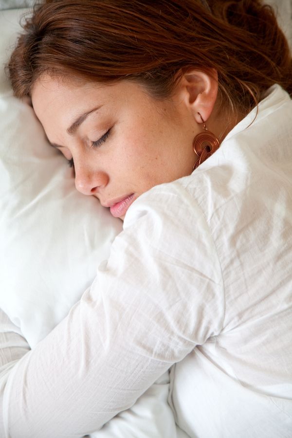 Person applying a sleek at-home sleep study device in a calm bedroom.