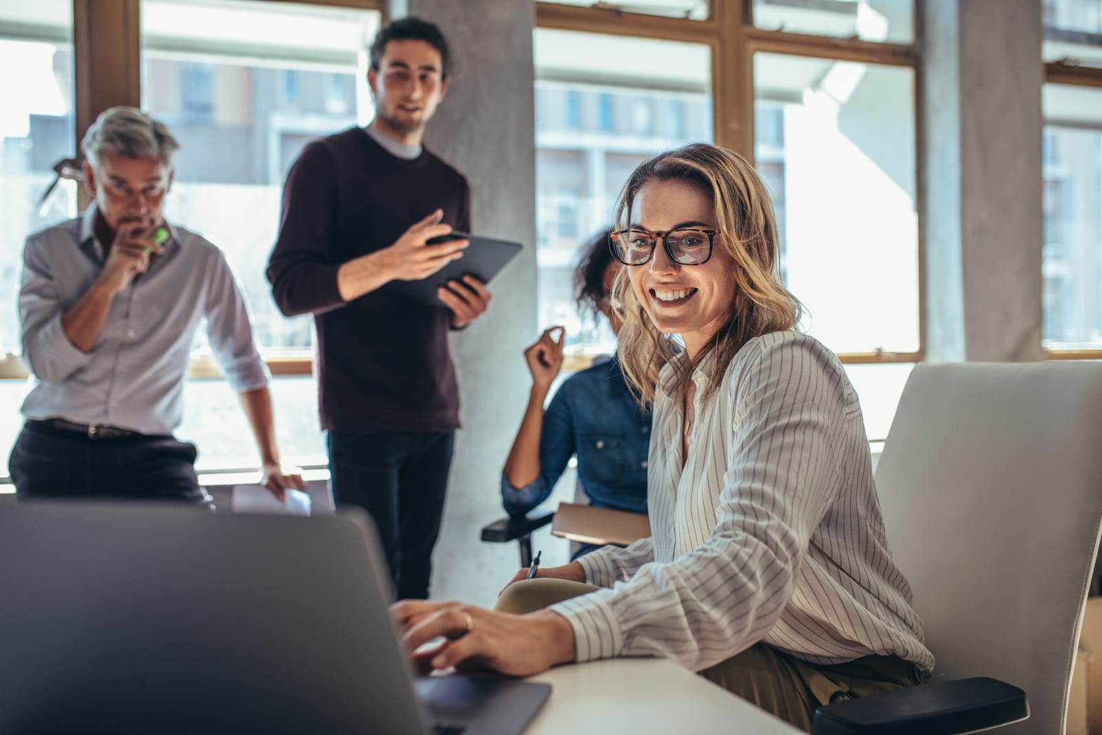 A team collaborating around a laptop in a bright office